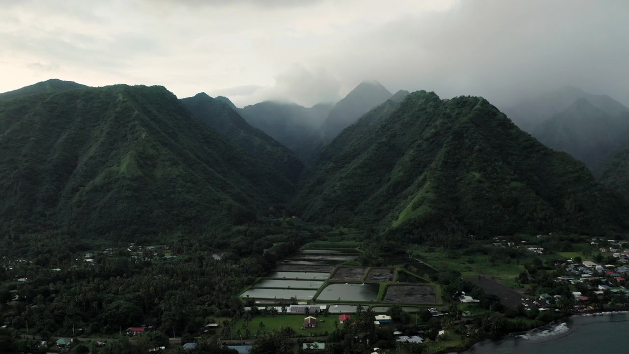 Teahupoo, Tahiti'nin üzerindeki ikiz sisli zirvelere doğru süzülen drone, nehir vadisi tabanını ve yağmur ormanı kanopisini yumuşak, bulutlu sabah ışığında çerçeveliyor.