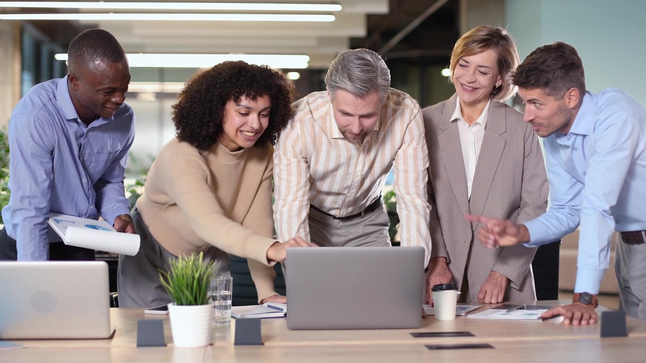 Diverse Business Team Collaborating and Discussing Around a Laptop in Office