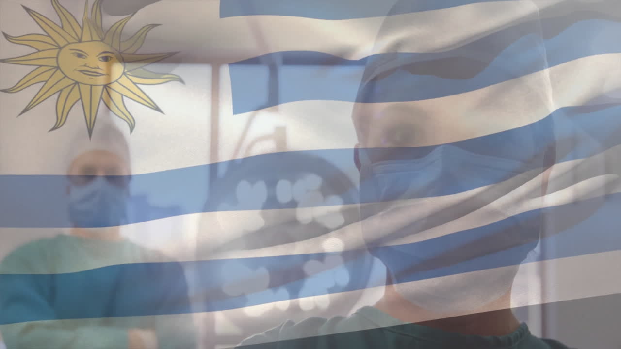 Animation of flag of uruguay over caucasian surgeons wearing face masks