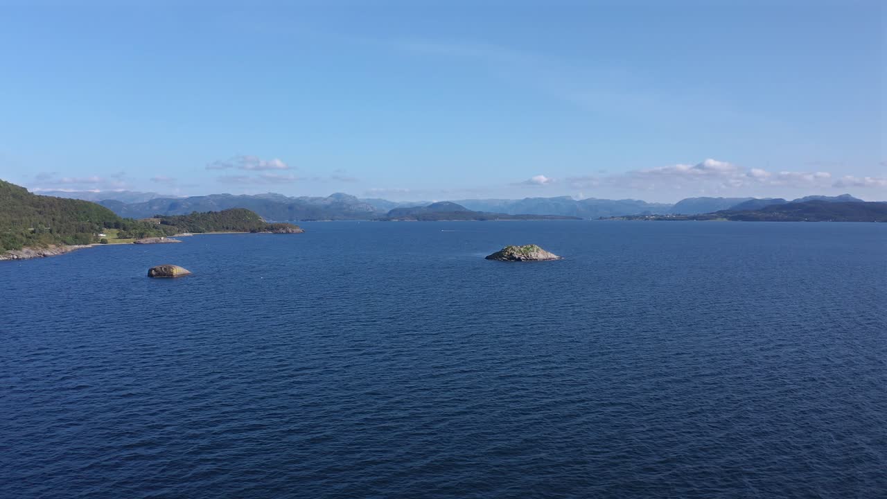 Calm ocean waters with distant islands and mountains, shot in Norway