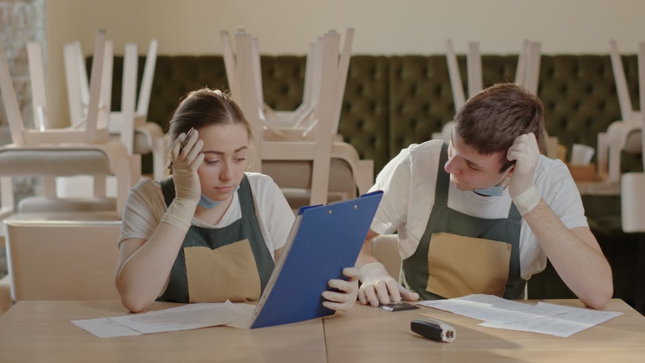 Stressed cafe workers making finance calculations