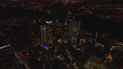 Forwards-fly-above-city-at-night.-Illuminated-group-of-tall-apartment-buildings.-Manhattan,-New-York-City,-USA