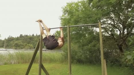 Young man performs window wipers exercise on home gym