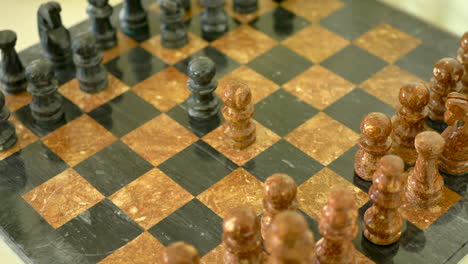 A-brown-and-black-stone-chess-set-in-the-early-stage-of-the-match-when-two-pawns-are-being-moved-into-the-center-as-a-strategic-position