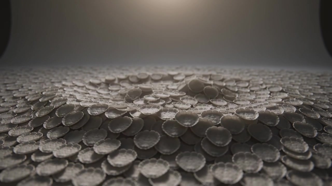 Un impulso invisibile che sale solleva la serie di dischi sul pavimento del ciclorama, formando due cumuli sotto una luce soffusa