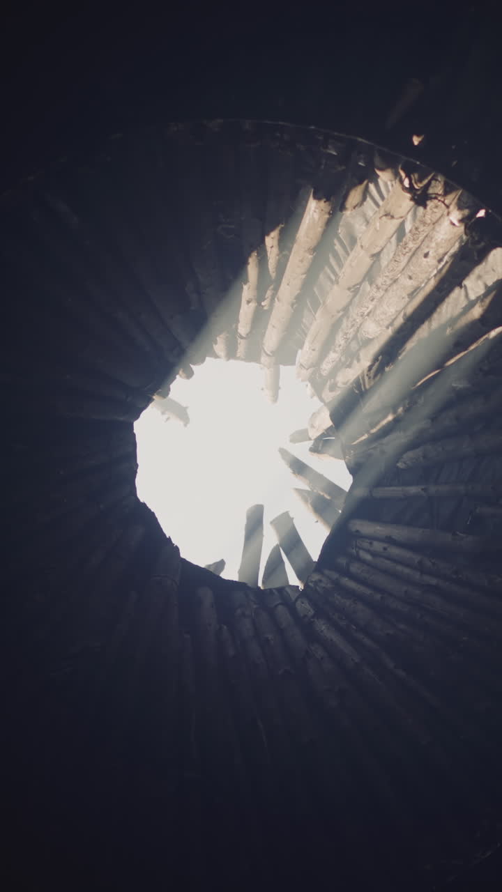 Open roof of dark ail traditional Altai house and glowing sunlight low angle shot. Ventilation hole in old ethnic building rooftop. Folk architecture