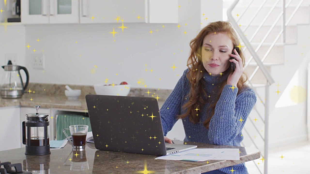 Woman taking call, typing on laptop and reading papers, gold stars overlaying business work