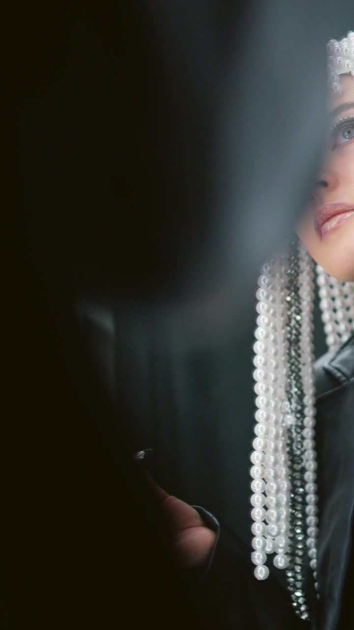 Woman with pearl headdress applying artistic eye makeup