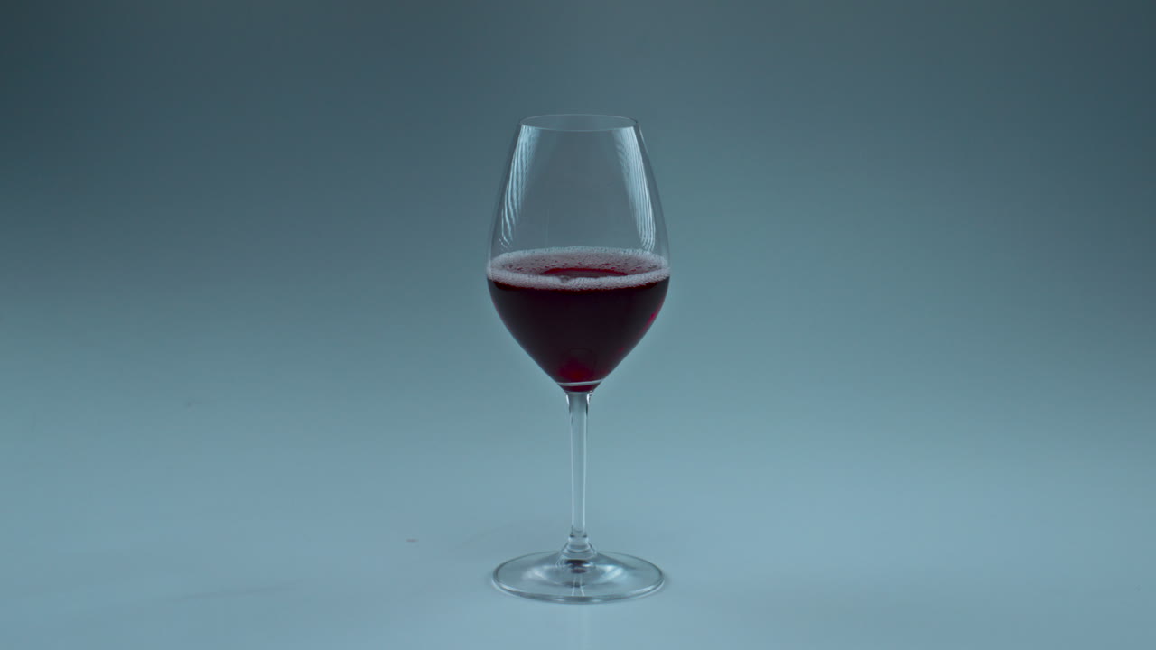primo piano goccia di vino rosso che cade dal bicchiere. goccia di rosa che schizza all'interno di una coppa pulita