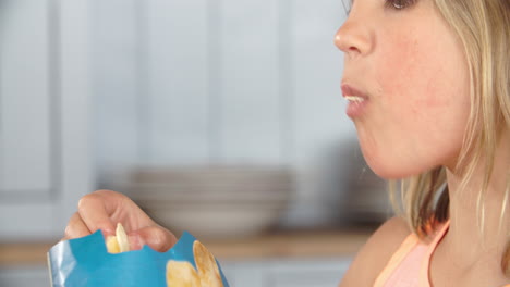 close up of girl eating packet of potato chips