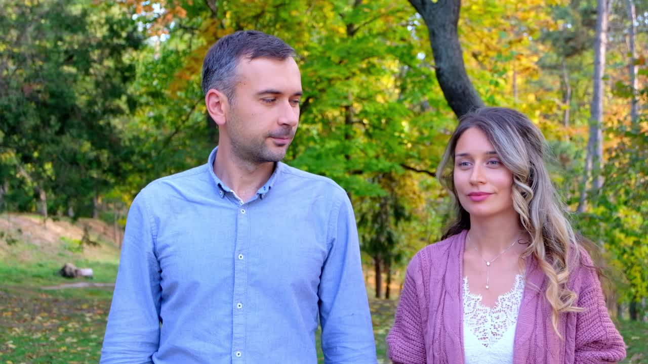 Happy mature couple walking in a park and looking at each other with love. Front view at sunlight. Relationships and feelings concept