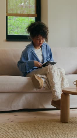 woman relaxing on a couch with a mug and tablet