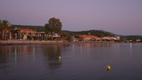 Blick-Auf-Strandhäuser-Mit-Violetten-Sonnenuntergangsfarben,-Die-Sich-Im-Meerwasser-Spiegeln