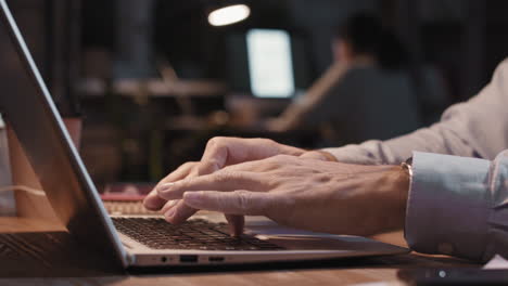 close-up of hands typing on laptop in an office