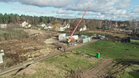 large telescopic crane assisting by the construction of a large villa on a sunny day