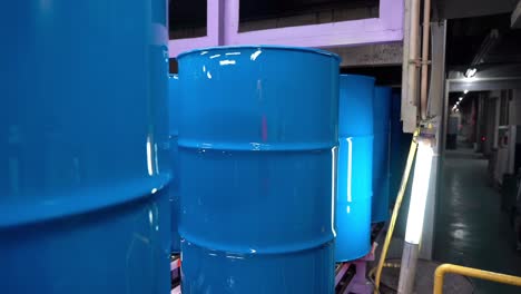 the steel drum cans gleam with a slow-transfer blue paint after their conveyor ride