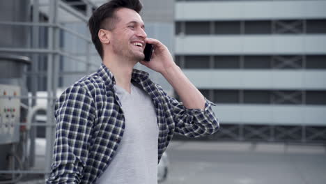 apuesto joven hablando por teléfono y riendo en la calle