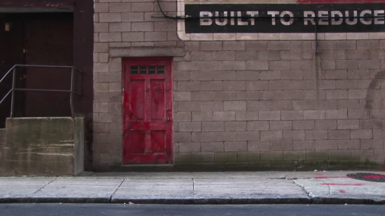 un joven camina por un edificio antiguo con una puerta roja