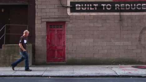 a young man walks by old building with a red door