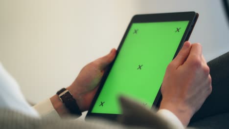 manos masculinas usando una tableta negra con pantalla verde y marcadores de seguimiento