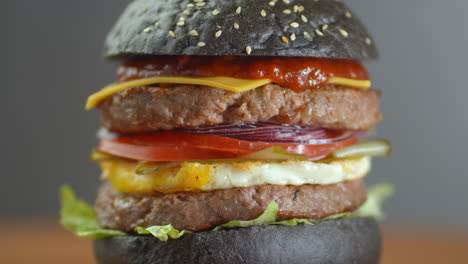 Black-Burger.-Ein-Burger-Mit-Schwarzen-Brötchen,-Saftigen-Marmor-Rindfleischscheiben,-Käse,-Frischem-Salat-Und-Barbecuesauce.