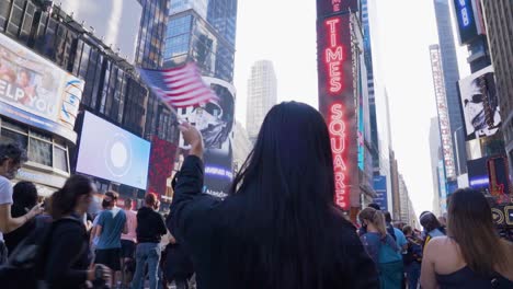 a young female waves an american flag during celebrations in times square after joe biden and kamala harris win the us presidential election in 2020.