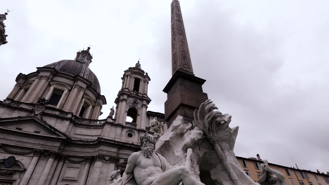 Fontana dei Quattro Fiumi With Obelisk And Sant'Agnese in Agone Church In Piazza Navona, Rome, Italy. - low angle shot