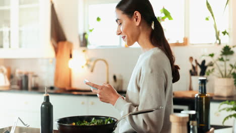 mujer usando el teléfono mientras cocina verduras en la cocina