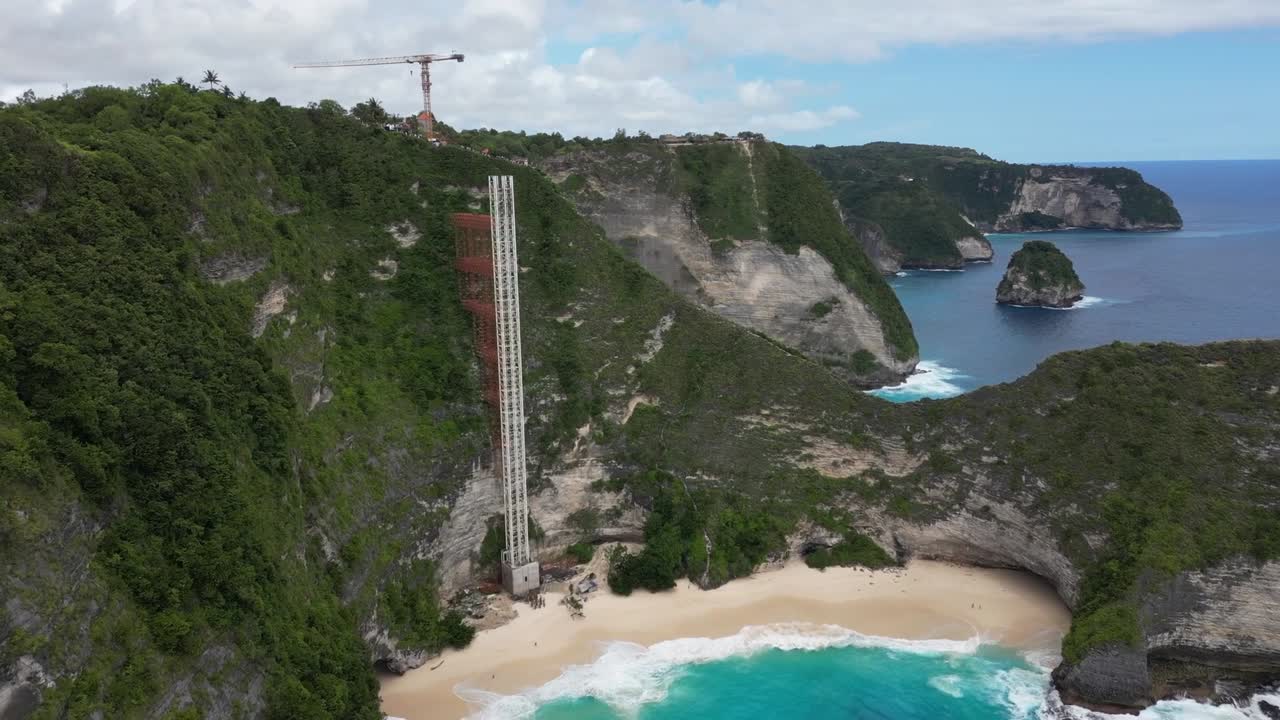 Eine sanfte Drohnenaufnahme vom Kelingking Strand, Nusa Penida, Bali, die den Bau des Aufzugs zeigt.