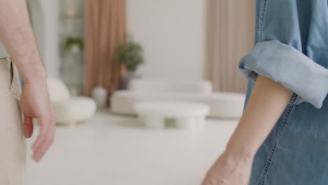 Back-View-Of-An-Unrecognizable-Couple-Standing-And-Holding-Hands-At-Home