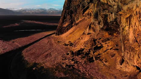 aerial shot of rockwall at iceland's black beach slowly descending