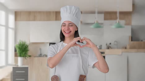 happy indian female professional chef making heart sign