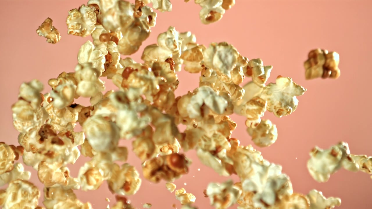Popcorn che volano al rallentatore su sfondo rosa
