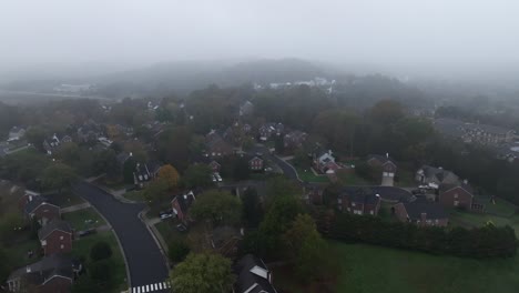 drone footage circling over a large neighborhood in the morning on a foggy day in the fall.