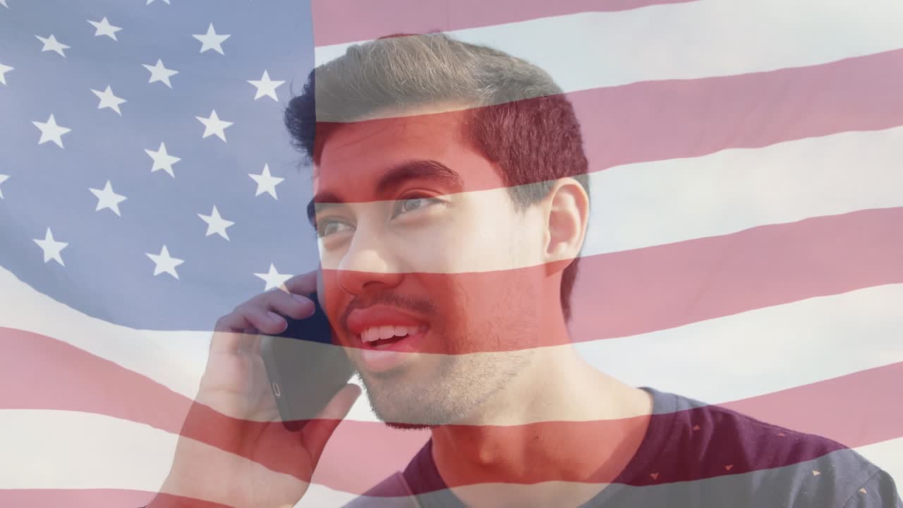 Animation of flag of america waving over close-up of smilng asian young man talking on cellphone