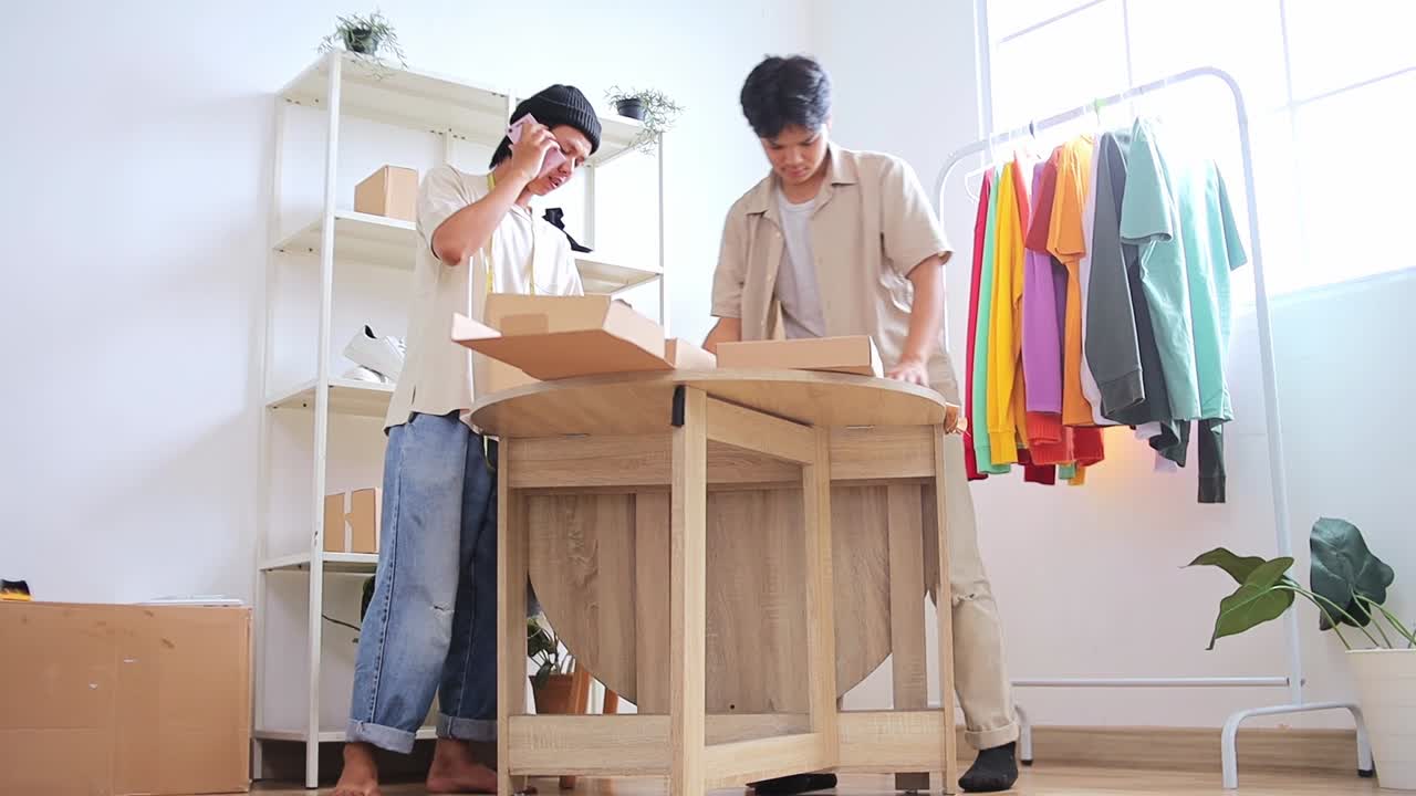 Dynamic young entrepreneurs packaging online orders in modern studio space full of clothing racks
