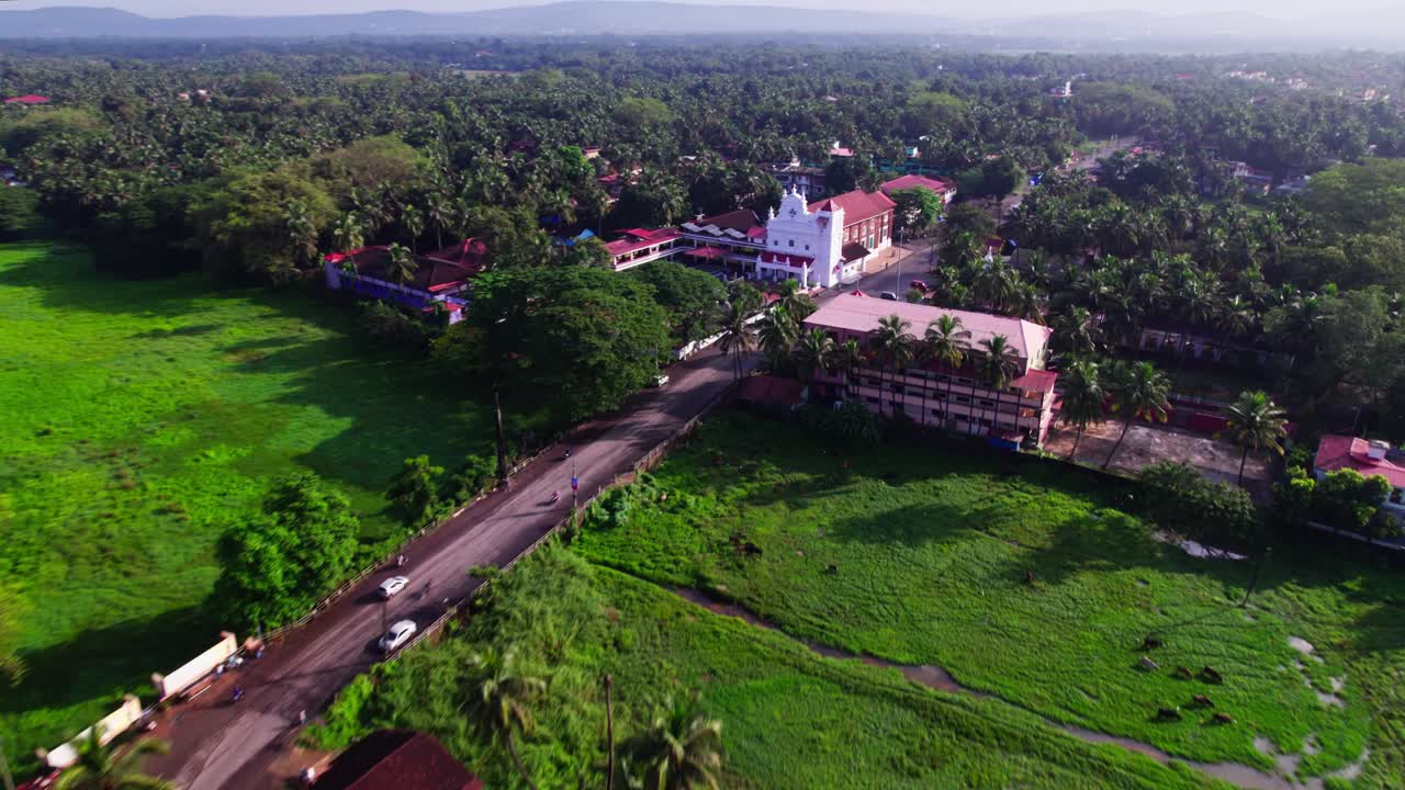 Houses with signal tower, lush greenery and Our Lady of Merces Church at Fatona, colva, goa, india. day time, push in shot, drone shot, 4k