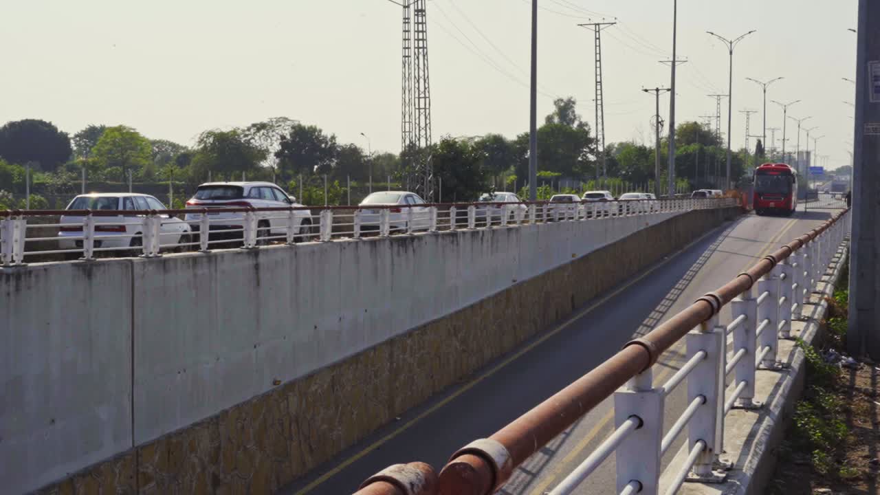 Panoramic view of a sleek City Metro Bus smoothly navigating down a curvaceous road into a modern underpass surrounded by lush greenery and scenic cityscape