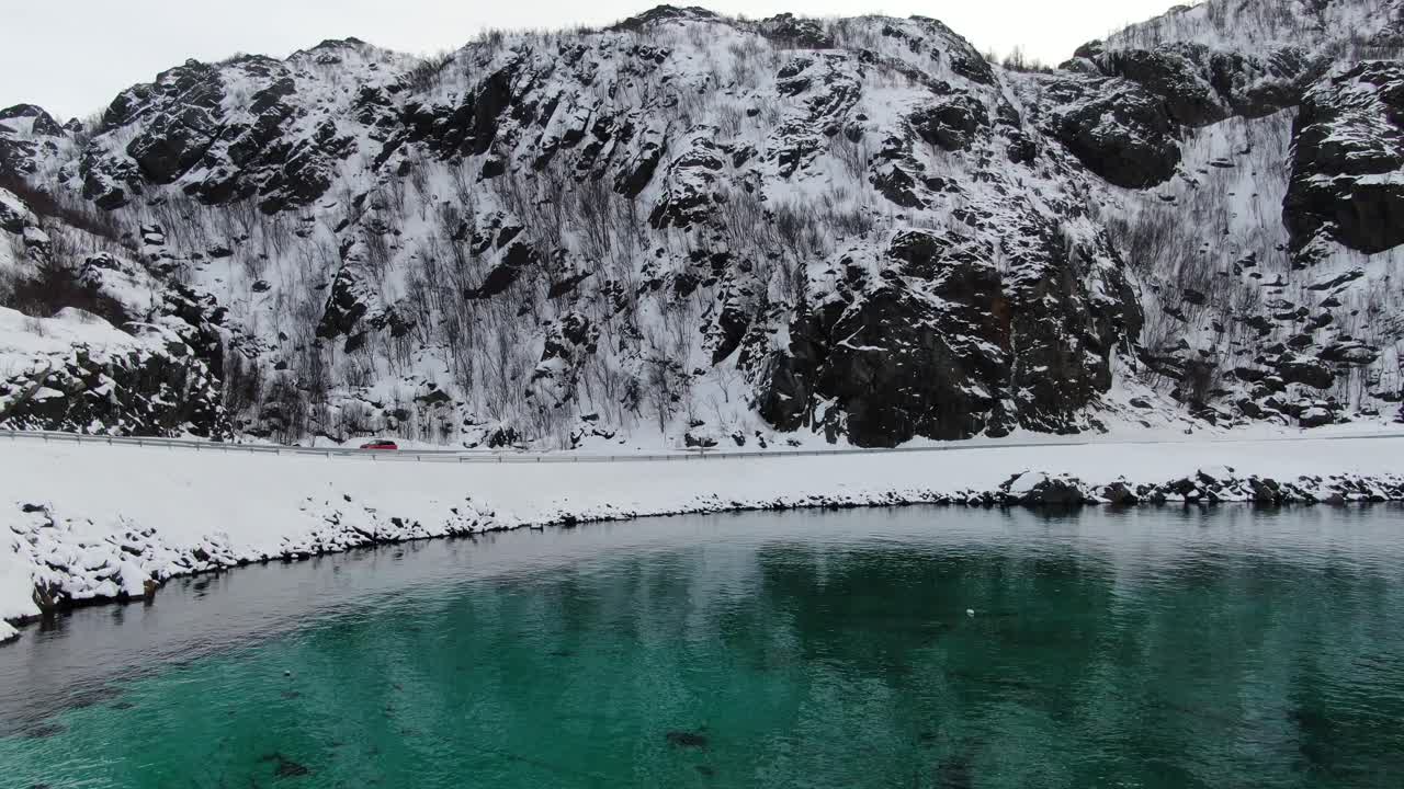 노르웨이 의 눈  ⁇ 인 산 들 과 함께 투르코이즈 색 의 투명 한 바다 를 날아다니는 겨울 에 트롬소 지역 의 드론 전망