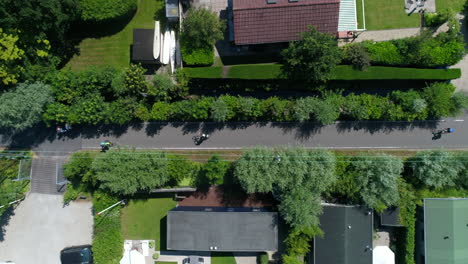 aerial view of bikers biking in the road along houses in the town near reeuwijkse plassen in netherlands