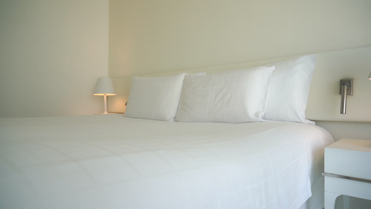 All White Kingsize Bed in Master Suite of Luxury Hotel, Pillows, Sheets and Lamp Pan Right