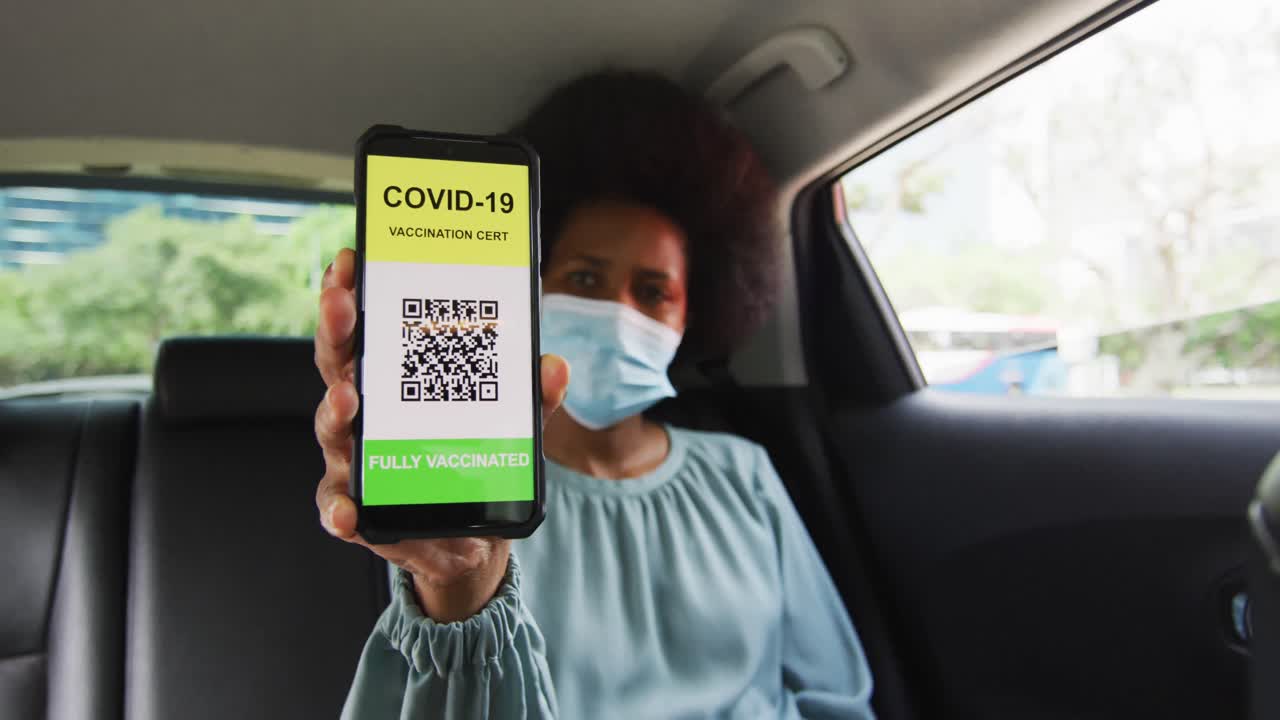 mujer de negocios afroamericana con máscara preparando la certificación de covid-19 en su teléfono inteligente