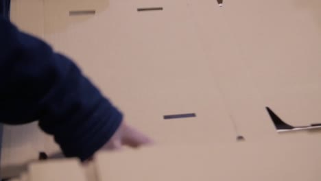 worker packing a cardboard box into a wooden crate