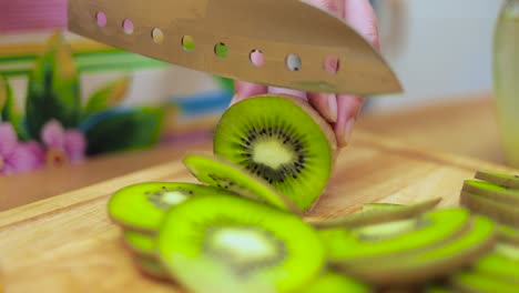 Women&#039;s hands Housewives cut with a knife fresh kiwi on the cutting Board of the kitchen table