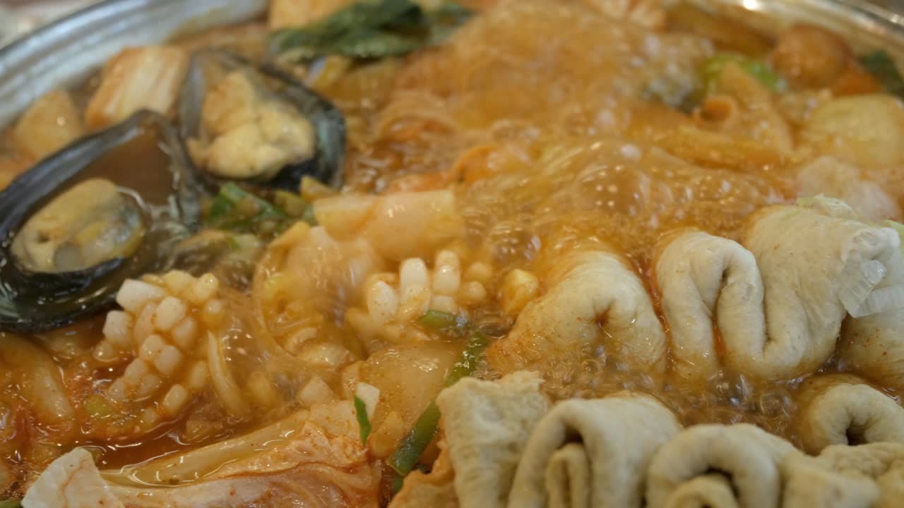 cerca de la sopa hirviendo de kimchi coreano tteok pokki llena de carne de cerdo, calamares, mejillones, plato de pescado y vegetales ehmook