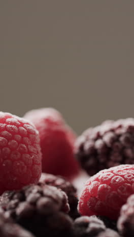 Micro vertical video close up of raspberries and copy space on grey background
