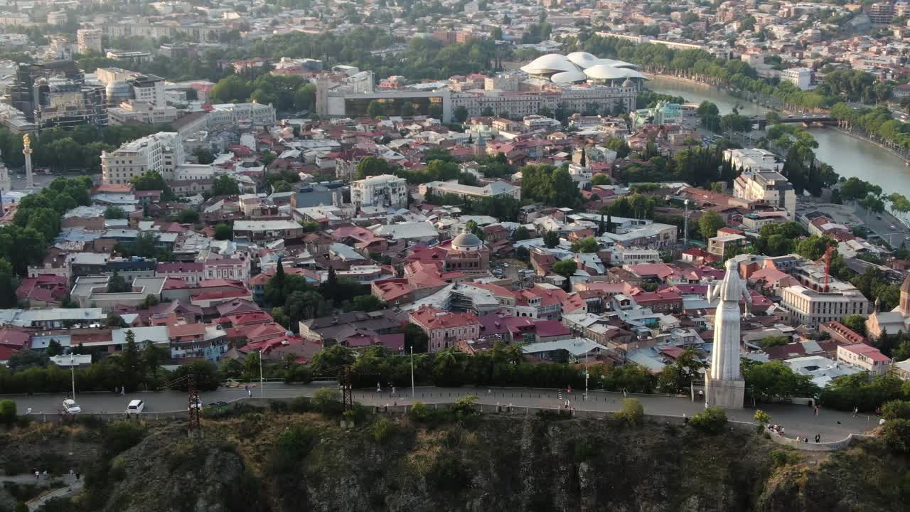 estatua de la madre de georgia mirando a la ciudad de tbilisi desde una cresta alta, vista de órbita aérea