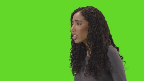 profile shot of angry looking woman shouting at camera against green screen