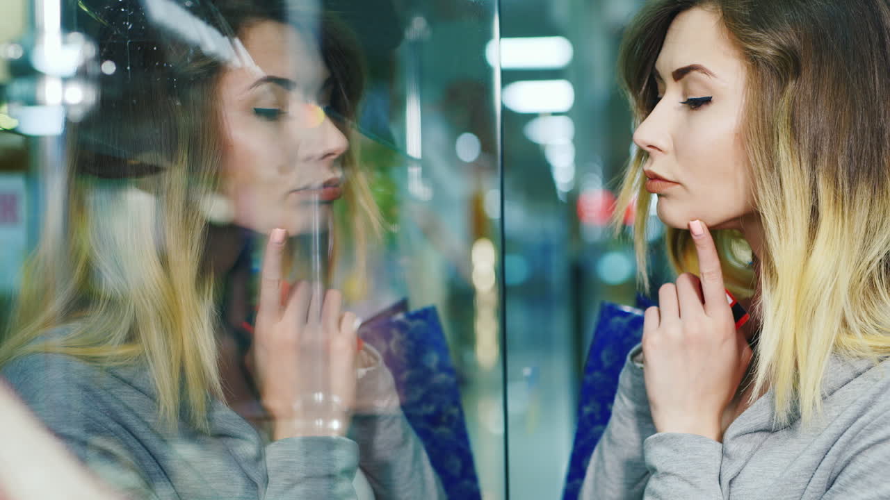 mujer atractiva considerando un escaparate en la ventana se ve su reflejo las manos sosteniendo th