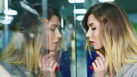 attractive woman considering a shop window in the window you see her reflection the hands holding th